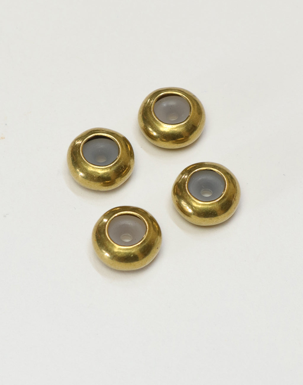 Four gold-tone and grey cabochon beads.