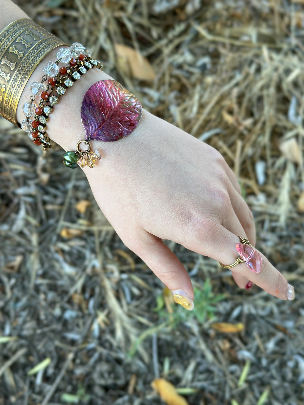 Hand wearing multiple bracelets and a ring.