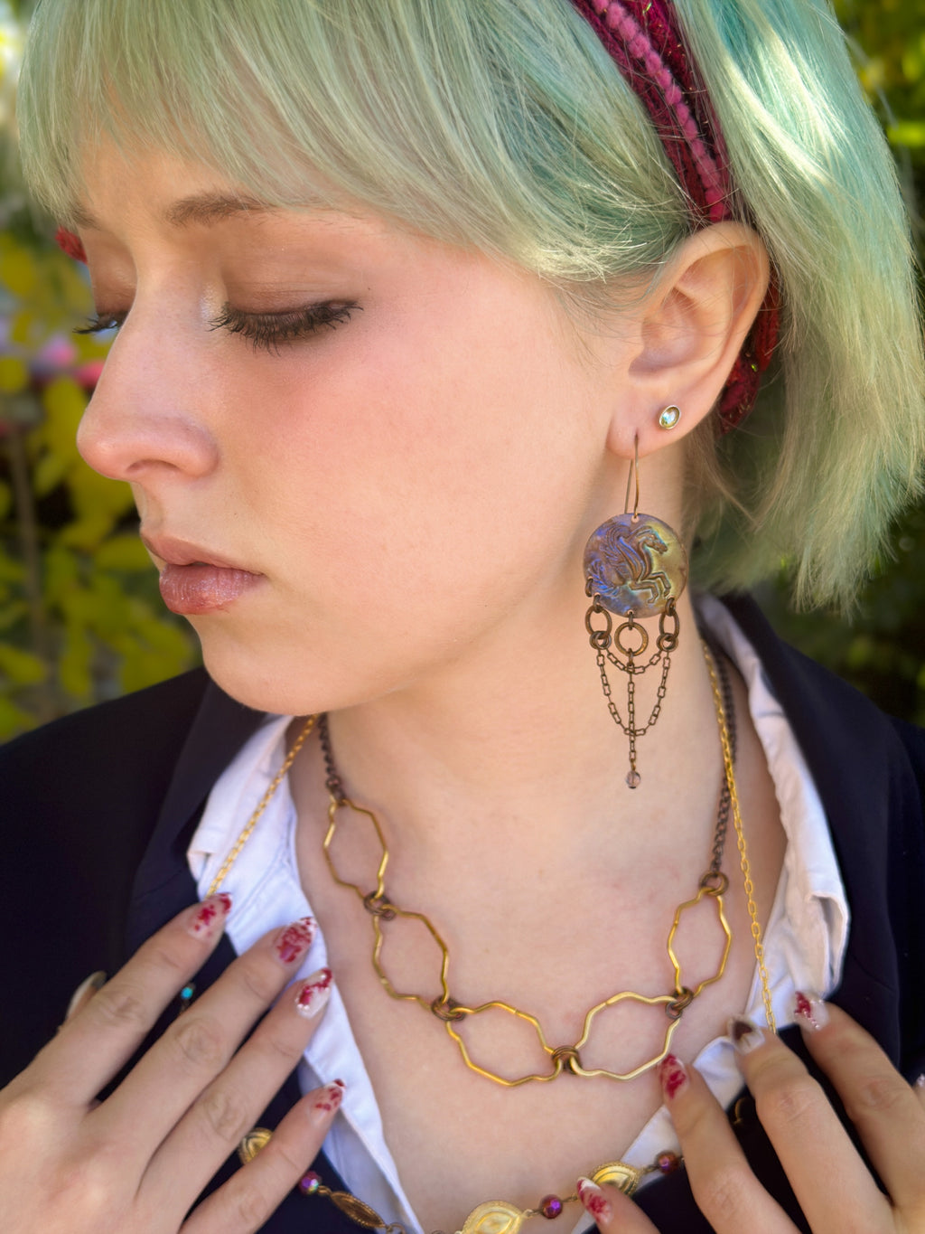 Woman with green hair, jewelry, and a blazer.