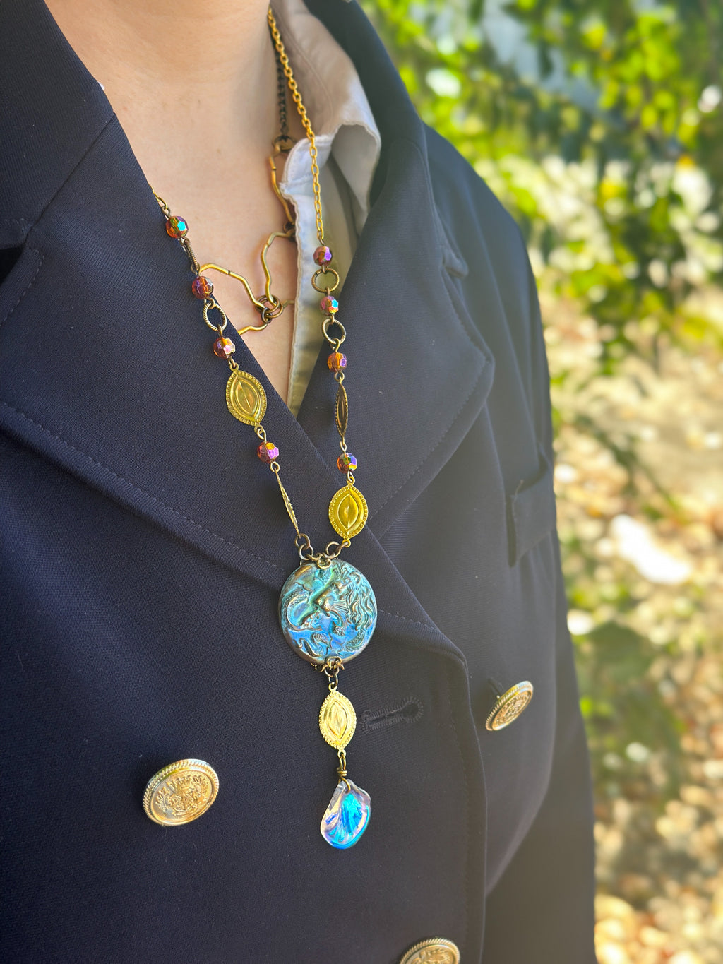 Woman wearing a long necklace and dark coat.