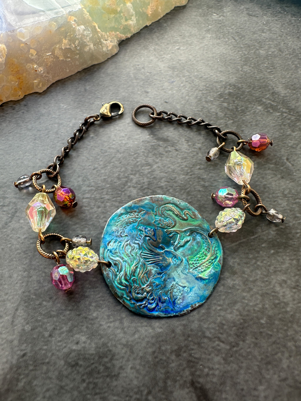 Bracelet with blue-green center and colorful beads.