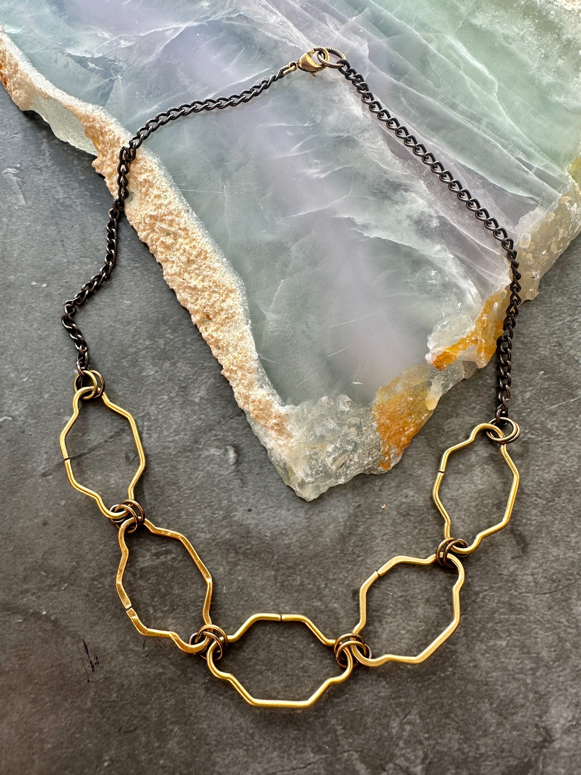Gold and black chain necklace with geometric pendants.