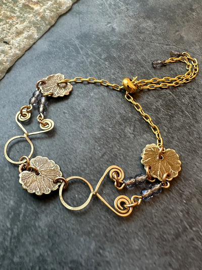 Gold bracelet with leaf charms and beads.