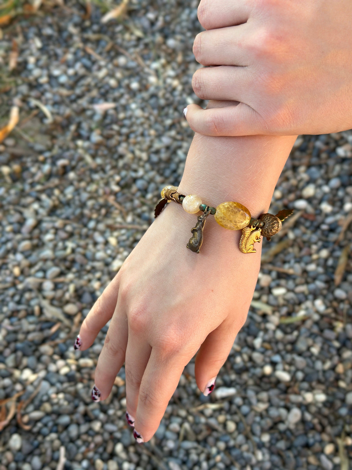 Hand wearing a beaded charm bracelet.
