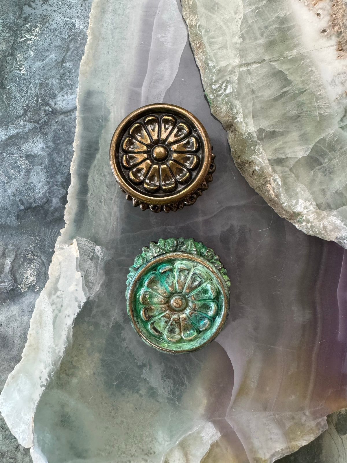 Two ornate, circular metal objects on a colorful, patterned stone.
