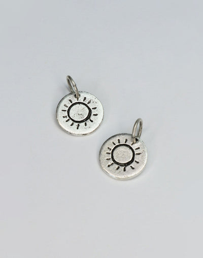 Two silver sun charm pendants