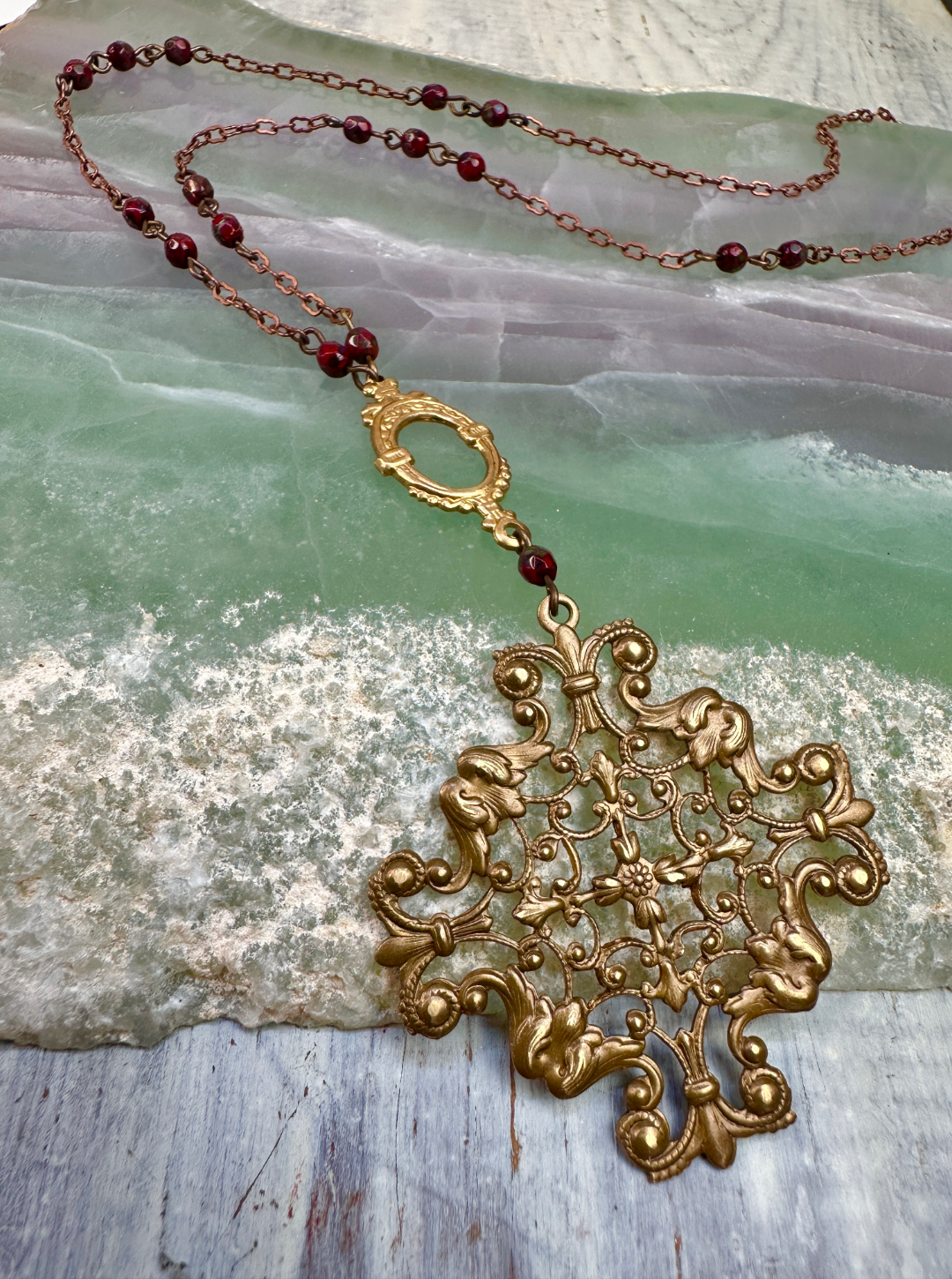 Ornate gold pendant necklace with red beads