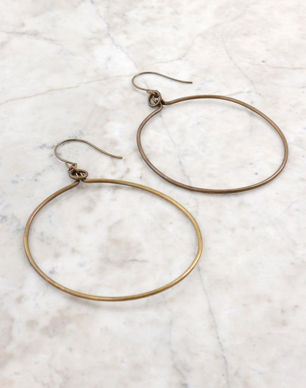 Gold hoop earrings on white marble
