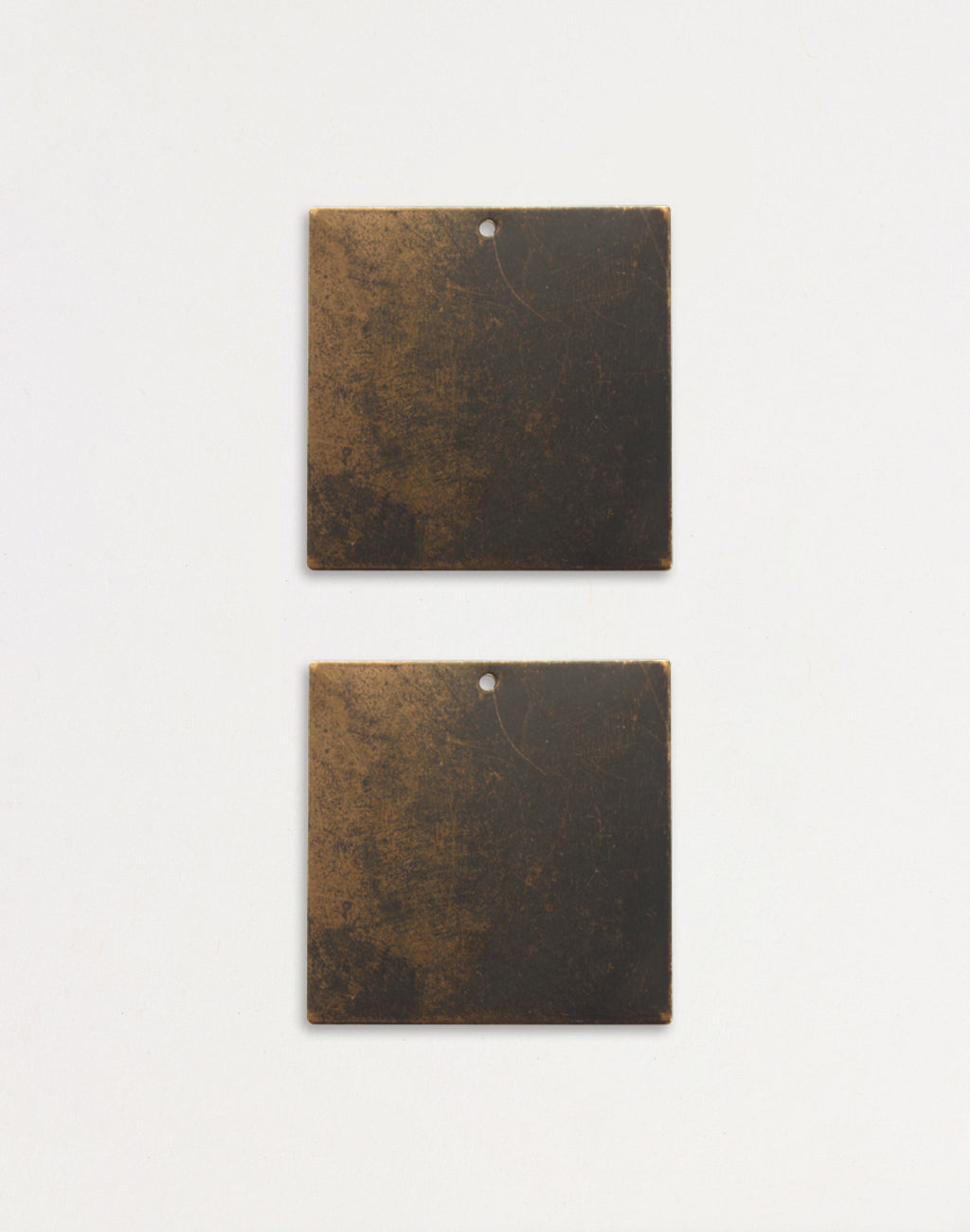 Two square metal tiles with aged finish